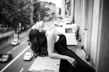 Siyah beyaz portre genç kadının zarif ipek siyah elbise bakıyordum bir şehir bir balkondan moda güzellik fotoğraf