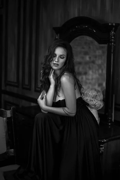 年轻女子的肖像在优雅的丝绸黑色礼服摆在黑暗的内部 时尚美容照片 — 图库照片