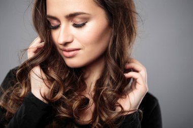 Esmer kız sağlıklı kıvırcık saçlı ve doğal makyaj. Güzel model kadınla dalgalı saç modeli. Bakım ve güzellik