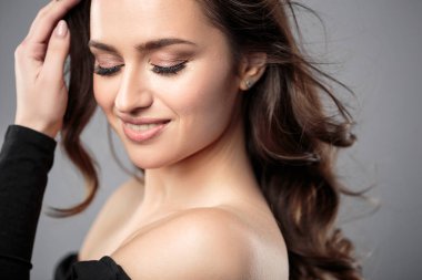 Esmer kız sağlıklı kıvırcık saçlı ve doğal makyaj. Güzel model kadınla dalgalı saç modeli. Bakım ve güzellik