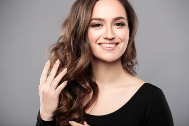 Esmer kız sağlıklı kıvırcık saçlı ve doğal makyaj. Güzel model kadınla dalgalı saç modeli. Bakım ve güzellik