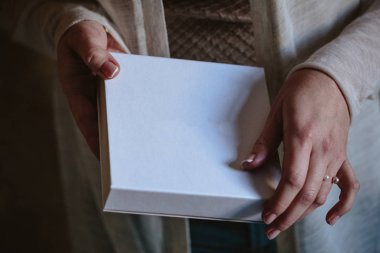Beyaz boş kutu içinde el yapımı takı düğün ile kadının ellerini tutun