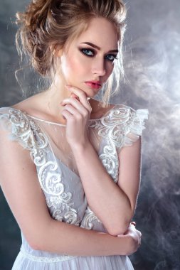 Zarif saç tarzı ile modern bir renk gelinlik gelin sarışın kadın ve makyaj. Dokulu arka plan üzerinde moda güzellik portre