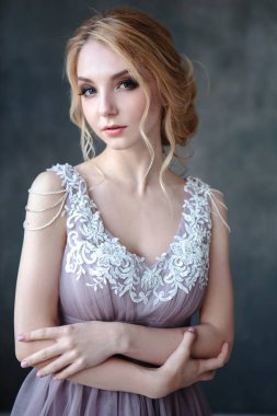 Zarif saç tarzı ile modern bir renk gelinlik gelin sarışın kadın ve makyaj. Dokulu arka plan üzerinde moda güzellik portre