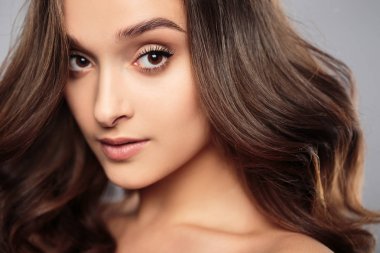 Esmer kız sağlıklı kıvırcık saçlı ve doğal makyaj. Güzel model kadınla dalgalı saç modeli. Bakım ve güzellik