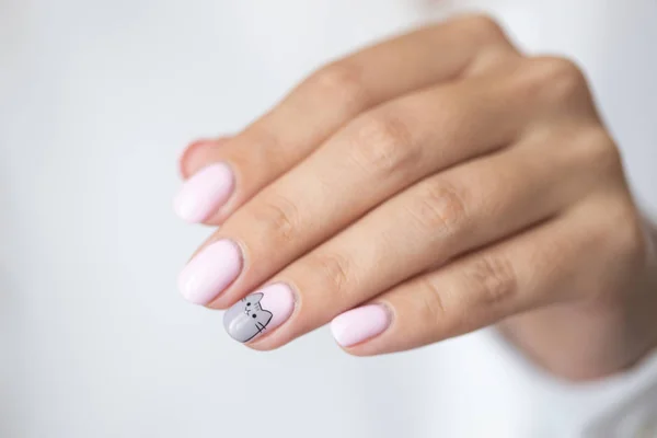 Close-up photo of elegant light pink manicure over white shirt background, tender women\'s hands with perfect nails, spa and care