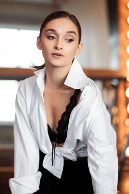 Genç esmer kadın büyük ayna yakınında poz. Mükemmel makyaj ve şık at kuyruğu, erkeksi stil, ince şekil