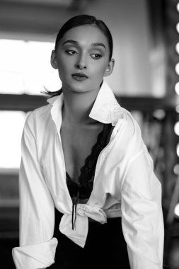 Genç esmer kadın büyük ayna yakınında poz. Mükemmel makyaj ve şık at kuyruğu, erkeksi stil, ince şekil