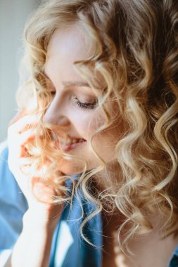 Kıvırcık saçlı ve doğal makyaj ile sarışın büyüleyici genç kadının portresi kadar kapatın. Güneşli sabah, spa ve bakım