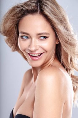 Sağlıklı kıvırcık saçlı ve doğal makyaj ile Sarışın genç kadın . Dalgalı saç modeli ile güzel model kız. Bakım ve güzellik