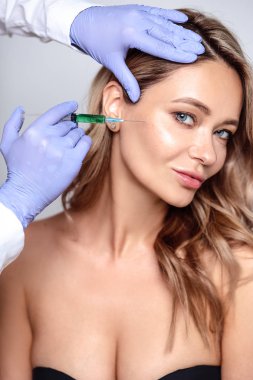 Yüzüne yakın kozmetolojist elleri ile sarışın kadının portresi kadar yakın. Salon, spa ve bakım da prosedür