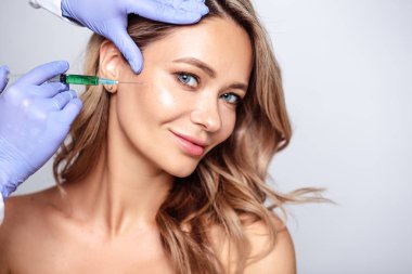 Yüzüne yakın kozmetolojist elleri ile sarışın kadının portresi kadar yakın. Salon, spa ve bakım da prosedür