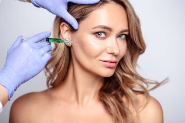 Yüzüne yakın kozmetolojist elleri ile sarışın kadının portresi kadar yakın. Salon, spa ve bakım da prosedür