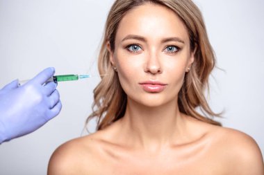 Yüzüne yakın kozmetolojist elleri ile sarışın kadının portresi kadar yakın. Salon, spa ve bakım da prosedür