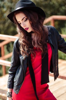 Kırmızı bir elbise ve doğa üzerinde poz siyah ceket esmer kadın parlak portre. Moda güzellik fotoğraf