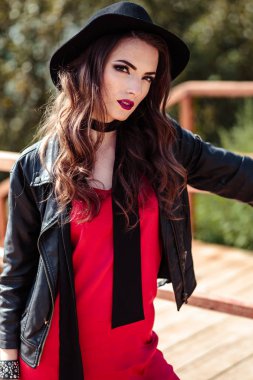 Kırmızı bir elbise ve doğa üzerinde poz siyah ceket esmer kadın parlak portre. Moda güzellik fotoğraf