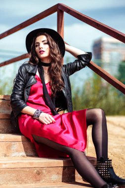 Kırmızı bir elbise ve doğa üzerinde poz siyah ceket esmer kadın parlak portre. Moda güzellik fotoğraf