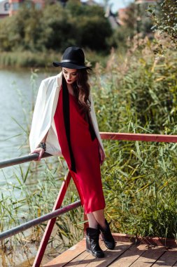 Kırmızı elbise ve beyaz ceket doğa üzerinde poz esmer kadın parlak portre. Moda güzellik fotoğraf