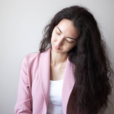 Açık pembe takım elbiseli, gülümseyen kadın portresi.