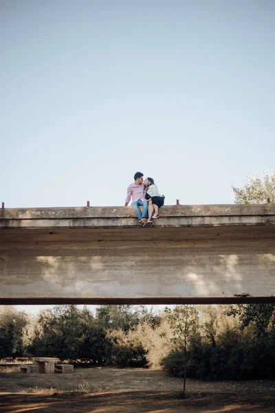 young couple in love kissing on an old bridge at sunset