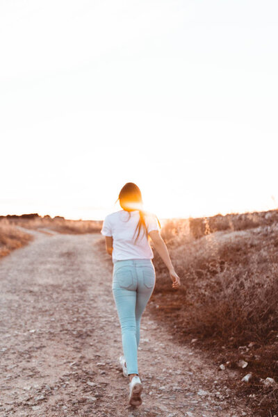 young woman running at sunset in the field