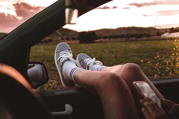 Jonge Vrouw Met Sneakers Met Voeten Gestut Autoruit Bij Zonsondergang — Stockfoto