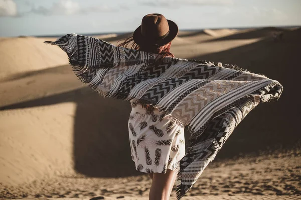 Giovane donna da dietro con sciarpa e cappello nel deserto al tramonto — Foto Stock