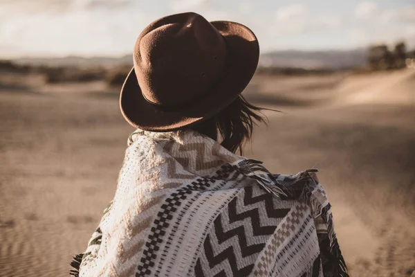 Mujer joven de atrás con bufanda y sombrero en el desierto al atardecer — Foto de Stock