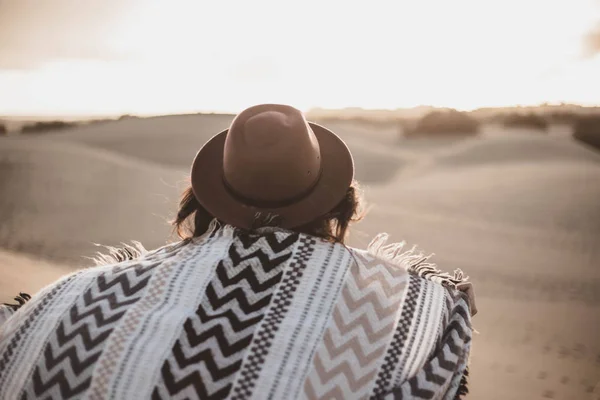 Mujer joven de atrás con bufanda y sombrero en el desierto al atardecer — Foto de Stock