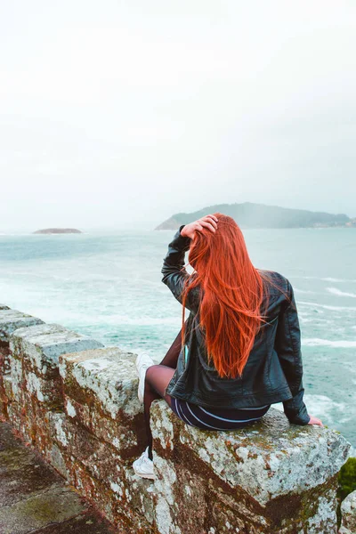 Giovane donna rossa che si tocca i capelli guardando il mare — Foto Stock