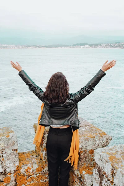 Mujer joven con los brazos abiertos en una fortaleza en el mar — Foto de Stock