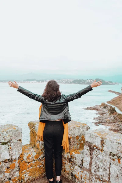 Mujer joven con los brazos abiertos en una fortaleza en el mar — Foto de Stock