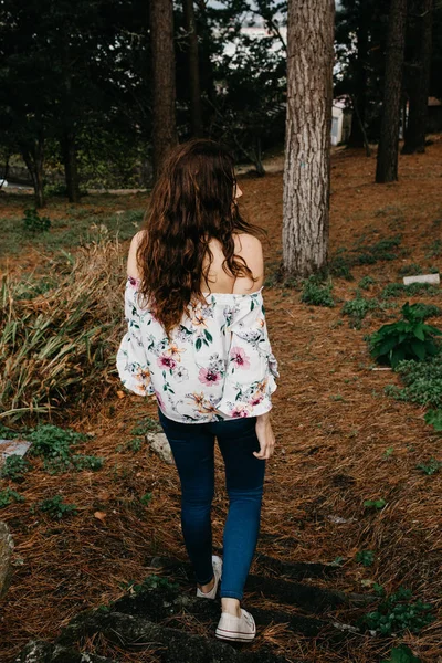 Mujer joven con el pelo rizado caminando por el bosque — Foto de Stock