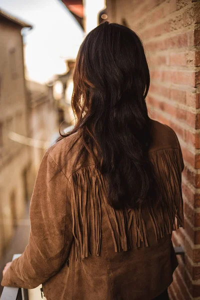 Mujer joven en su espalda con el pelo largo y negro en el balcón en una ciudad vieja — Foto de Stock