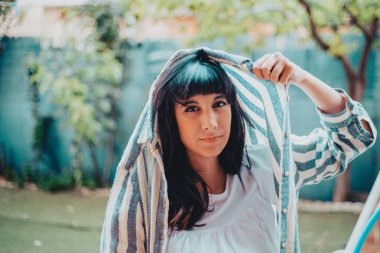 Genç bir kadın yağmurdan korunmak için başını gömlekle örtüyor.