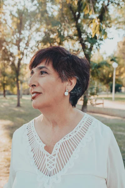 Close up portrait of lovely hispanic middle aged woman in the park — Stock Photo, Image