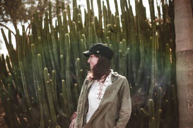 model kaktüs yakınında siyah kap ile gülümseyen