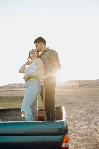 Pareja joven con besos de guitarra en la parte superior del coche jeep 4x4 al atardecer —  Fotos de Stock