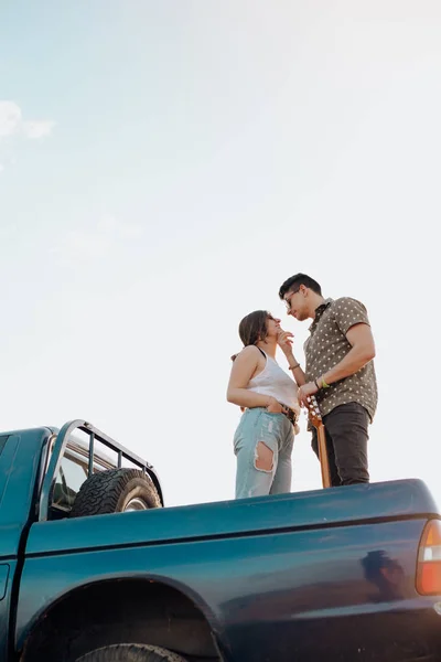 Hermosa pareja joven besándose en la parte superior del jeep 4x4 coche en la puesta del sol —  Fotos de Stock