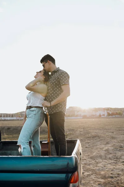 Красива молода пара цілується на джипі 4x4 автомобіля на заході сонця — стокове фото