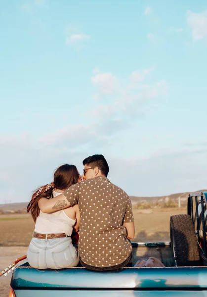 Young travelers lovers having hugging and kissing on top of jeep 4x4 car. Couple making a wanderlust vacation at summer — Stok fotoğraf