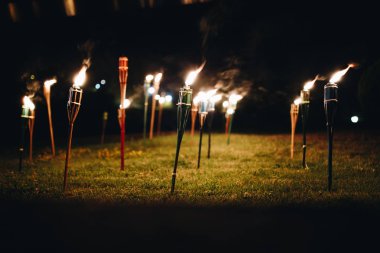 Burning torches at night in the grass with yellow flames and highlights clipart