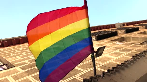 Regenbogenfahne Weht Gegen Blauen Himmel Der Stadt — Stockvideo