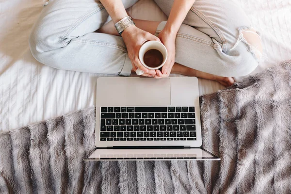 Невизнана жінка п'є каву і дивиться фільм на своєму ноутбуці — стокове фото
