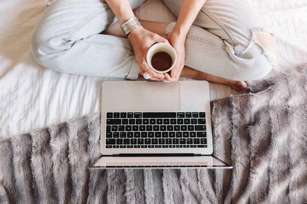 Unrecognized woman drinking coffee and watching movie on her laptop Stock Photo