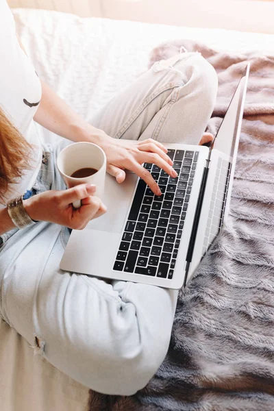 Непризнанная женщина пьет кофе и пишет на своем ноутбуке Лицензионные Стоковые Фото