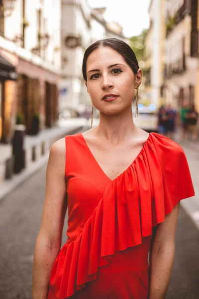 Portrait of beautiful brunette young woman with topknot hairstyle wearing red ruffles dress walking on the street. Fashion photo. Royalty Free Stock Photos