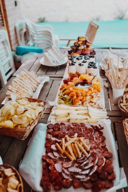 Chorizo, salam, peynir, cips, ekmek, sandviç, çörek, yoğurt, meyve çikolata fondü mandalina, muz, kivi, yaban mersini, çilek ahşap bir masada ile kesme tahtası Closeup