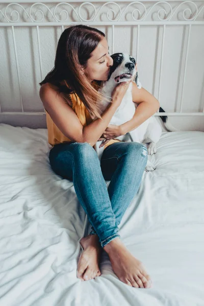 Szép nő megcsókolta a Labrador kiskutya az ágyban. A Labrador kiskutya van karjaiban. — Stock Fotó