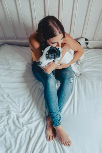 快乐的女人在床上抚摸拉布拉多小狗。拉布拉多小狗在她的怀里. — 图库照片